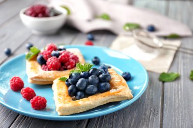 Ahşap masa üzerinde nefis berry puf böreği ile plaka