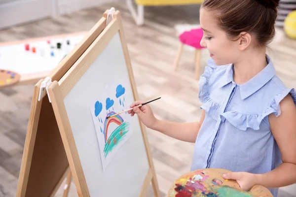 Kleine meisje schilderij regenboog thuis — Stockfoto