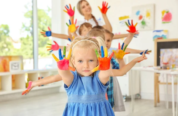 Los niños y el maestro con las manos en pintura en la lección de arte — Foto de Stock