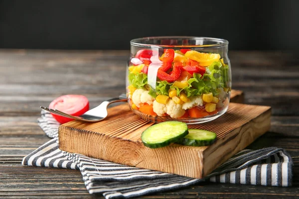 Delicious vegetable salad in jar on wooden board