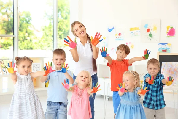 Kinderen en leerkrachten met handen in verf op kunst les — Stockfoto