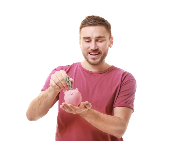 Joven poniendo billete en alcancía sobre fondo blanco — Foto de Stock