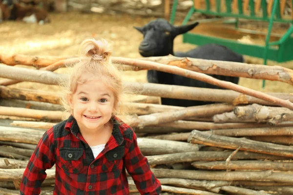 Cute little girl near enclosure with goats on farm — Stock Photo, Image