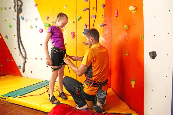 Entrenador ayudando a la niña a poner en marcha en el gimnasio de escalada — Foto de Stock