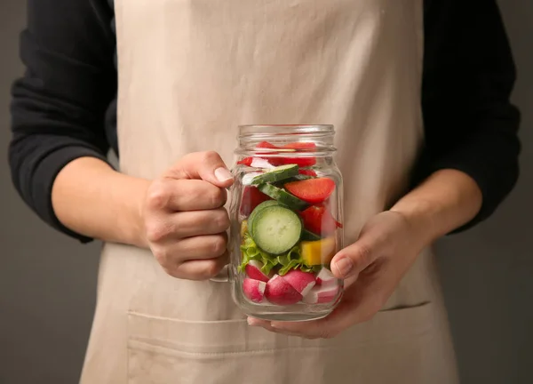 Nő a gazdaság befőttesüvegbe ízletes zöldség saláta — Stock Fotó