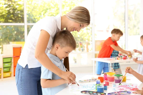 Маленький хлопчик з учителем на уроці малювання в класі — стокове фото