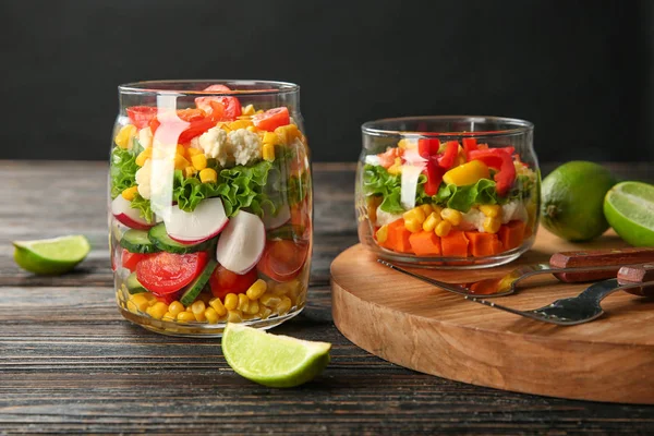 Delicious vegetable salad in jars on table