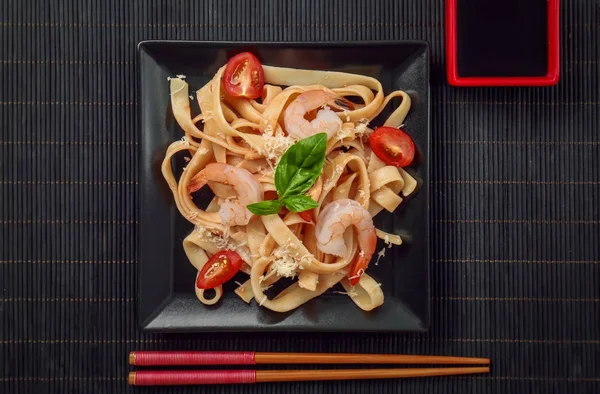 Plate of tasty pasta with shrimps on table, top view