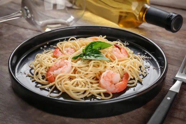 Plate of tasty pasta with shrimps on wooden table