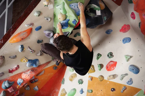 Hombre joven haciendo ejercicio en el gimnasio de escalada — Foto de Stock