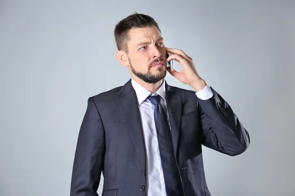 Stock exchange broker talking on phone against light background — Stock Photo, Image