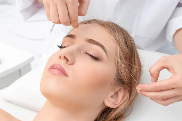 Young woman having eyebrow correction procedure in beauty salon — Stock Photo, Image