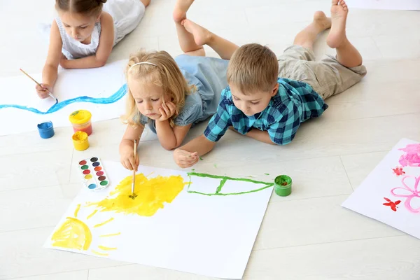 Kinderen liggend op de vloer in lichte kamer en schilderen — Stockfoto