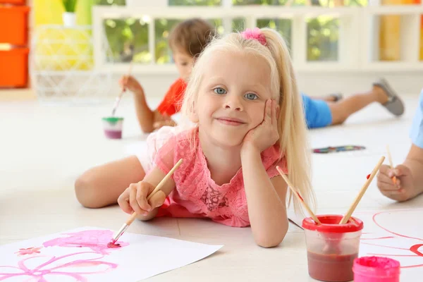 Petite fille couchée sur le sol dans la salle de lumière et la peinture — Photo