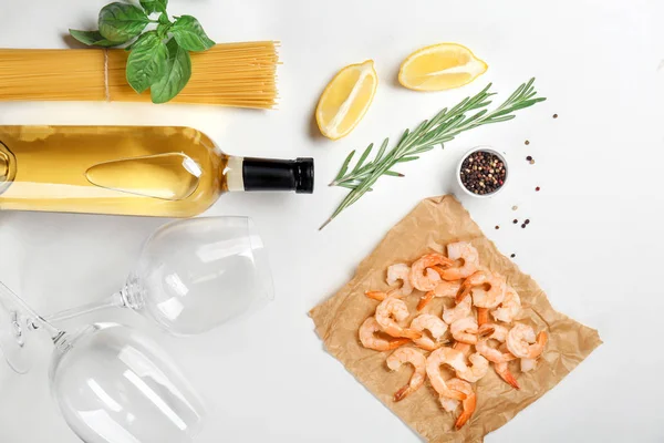 Composition with wine and ingredients for shrimp pasta on white background, top view