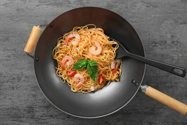Wok with tasty pasta and shrimps on table, top view