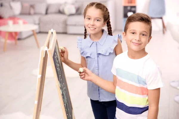 Evde kara tahta çizim kız kardeşi ile küçük çocuk — Stok fotoğraf