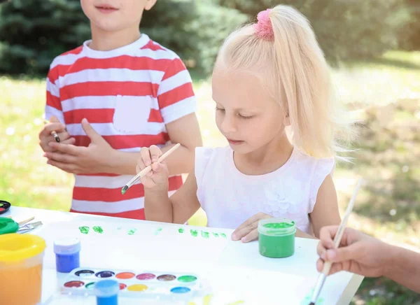 Маленькая девочка рисует на открытом воздухе вместе с друзьями — стоковое фото