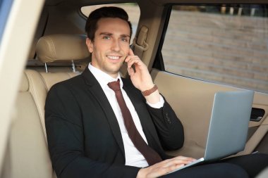 Adam telefonu arabada konuşurken laptop ile formal giyim