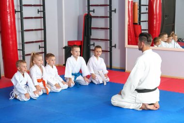Male karate instructor with little children in dojo clipart