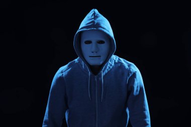 Karanlık arka planda maskeli bir bilgisayar korsanı