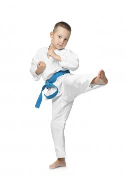 Küçük çocuk beyaz arka planda karate yapıyor.