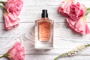 -Bir şişe parfüm ve ahşap zemin üzerine taze çiçekler