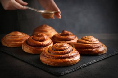 Kadın yağmurlama tatlı tarçın ile kayrak plaka üzerinde rulo.