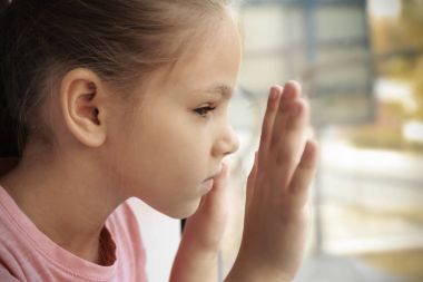 Pencere yakınındaki küçük üzgün kız. Kötüye çocuk kavramı