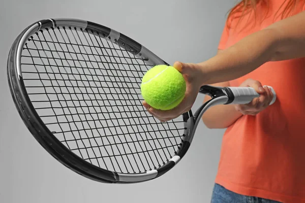 テニス ラケット、ライトグレーの背景の上にボールを持つ女性 — ストック写真