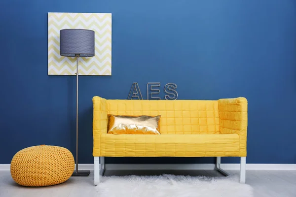Stylish yellow sofa on color wall background