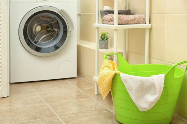 Basket with laundry and washing machine indoors — Stock Photo, Image