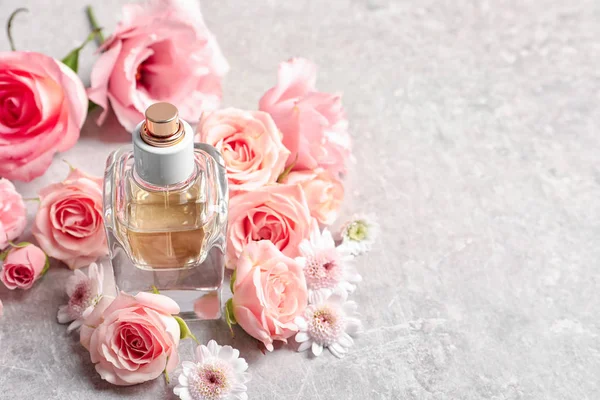 Flaska parfym med blommor på ljus bakgrund — Stockfoto