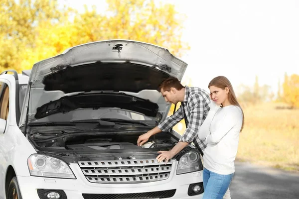 Giovane coppia in piedi vicino rotto auto all'aperto — Foto Stock