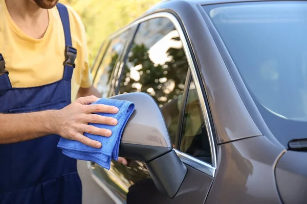 Man cleaning car rear view mirror with rag outdoors — Stock Photo, Image