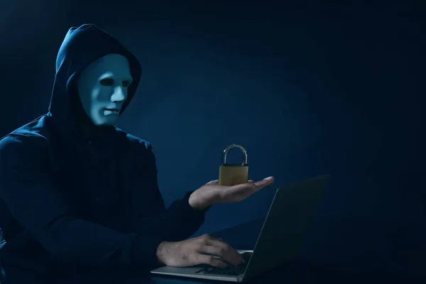 Hacker com bloqueio usando laptop no fundo escuro — Fotografia de Stock