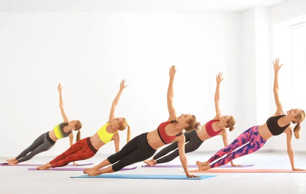Gruppe junger Frauen praktiziert Yoga im hellen Raum — Stockfoto