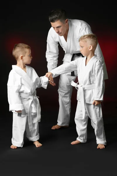 Karate koyu arka plan üzerinde pratik eğitmen ile küçük çocuk — Stok fotoğraf