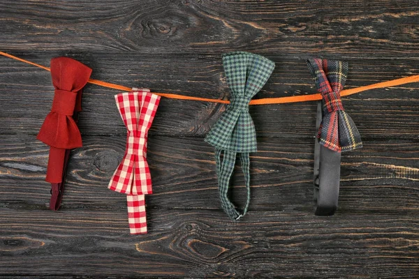 弓领带悬挂在绳子上的木制背景。快乐父亲节概念 — 图库照片