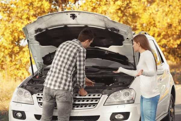 Junges Paar steht neben kaputtem Auto im Freien — Stockfoto