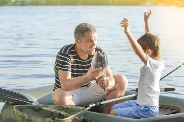 Vader en zoon vissen vanaf de boot op de rivier — Stockfoto