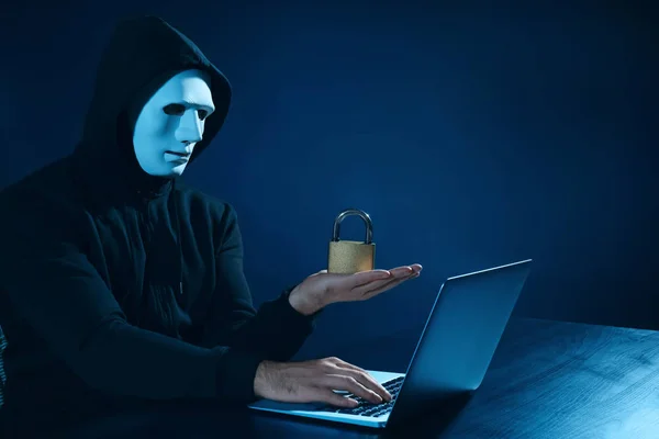 Hacker z zamkiem za pomocą laptopa na ciemnym tle — Zdjęcie stockowe