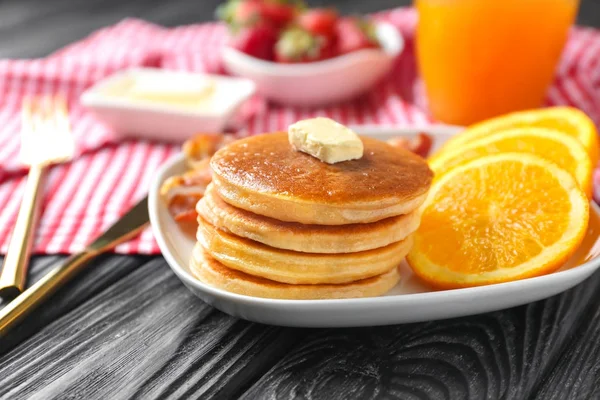 Placa con deliciosos panqueques y naranja sobre mesa de madera — Foto de Stock