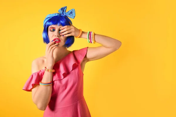 Młoda kobieta z włosów makijaż i niebieski tęcza na żółtym tle — Zdjęcie stockowe