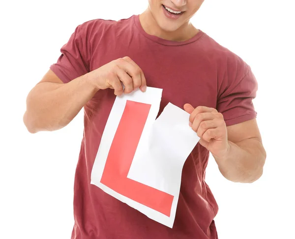 Jeune homme déchirant signe de conducteur apprenant sur fond blanc — Photo