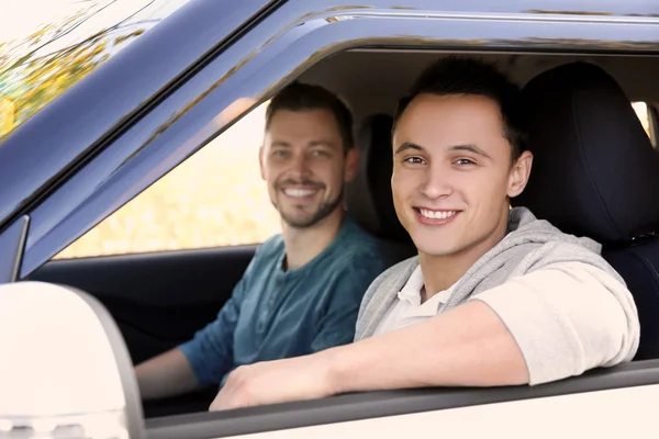 Jovem sentado no carro com instrutor de condução — Fotografia de Stock