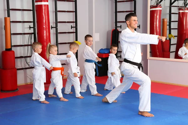 Maschio istruttore di karate formazione bambini piccoli in dojo — Foto Stock