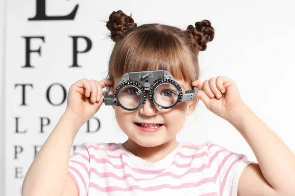 Милая маленькая девочка с пробной рамкой в кабинете офтальмолога — стоковое фото