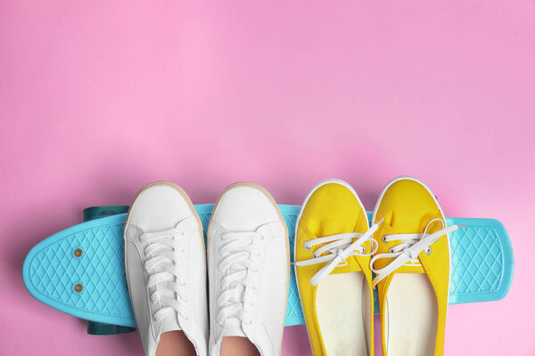 Female sport shoes with skateboard on color background