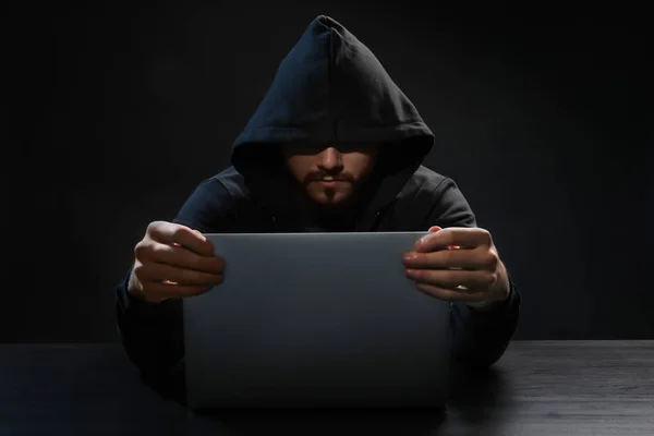 Hacker met behulp van laptop op donkere achtergrond — Stockfoto